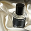 Lunar Dust perfume bottle resting on ivory silk