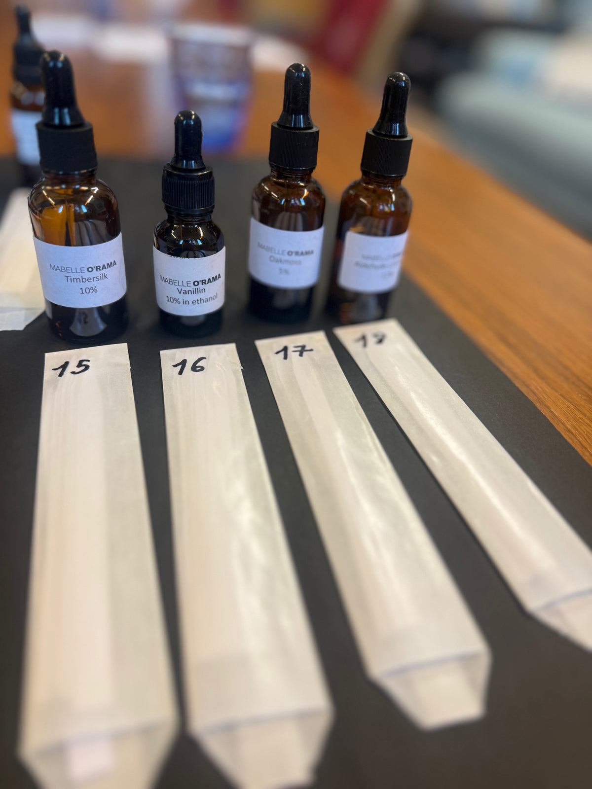 Dropper bottles of raw materials with numbered scent strips at a workshop